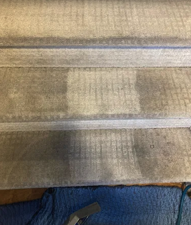Stair carpet cleaning detail showing a cleaned step beside a dirty one